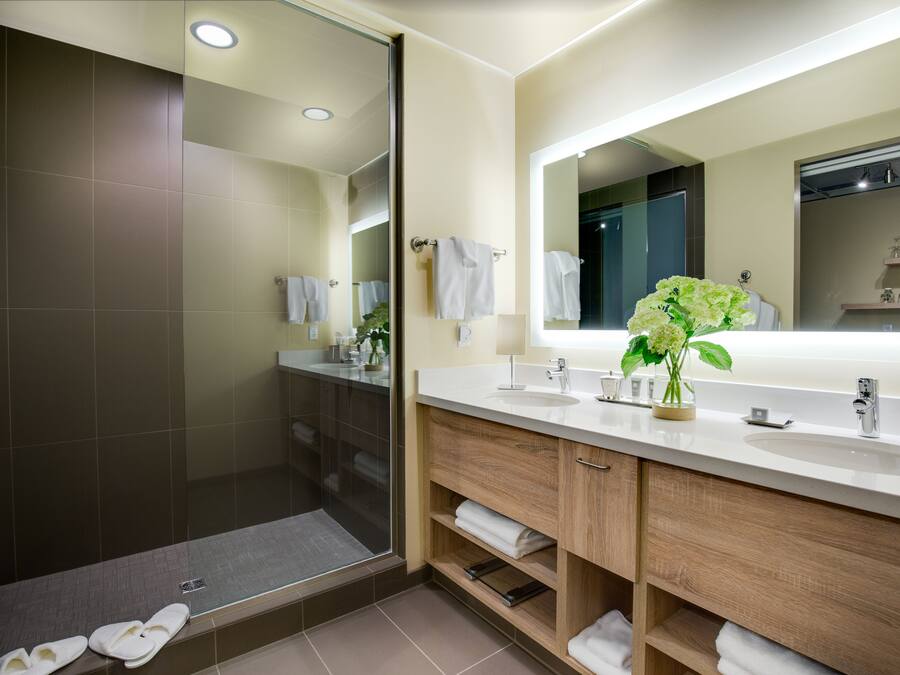 A modern bathroom with a walk-in shower, a large mirror, and a vanity with a sink and towel rack.