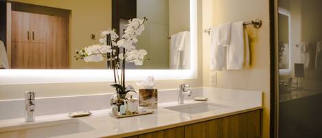 A modern bathroom with two sinks, a large mirror, and a wooden vanity.