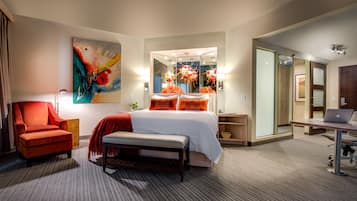 Ein Hotelzimmer mit Bett, Schreibtisch, Stuhl, Bank, Gemälde und Spiegel.