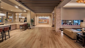 A modern kitchen with a wooden floor, a stone accent wall, and a large window overlooking the city.