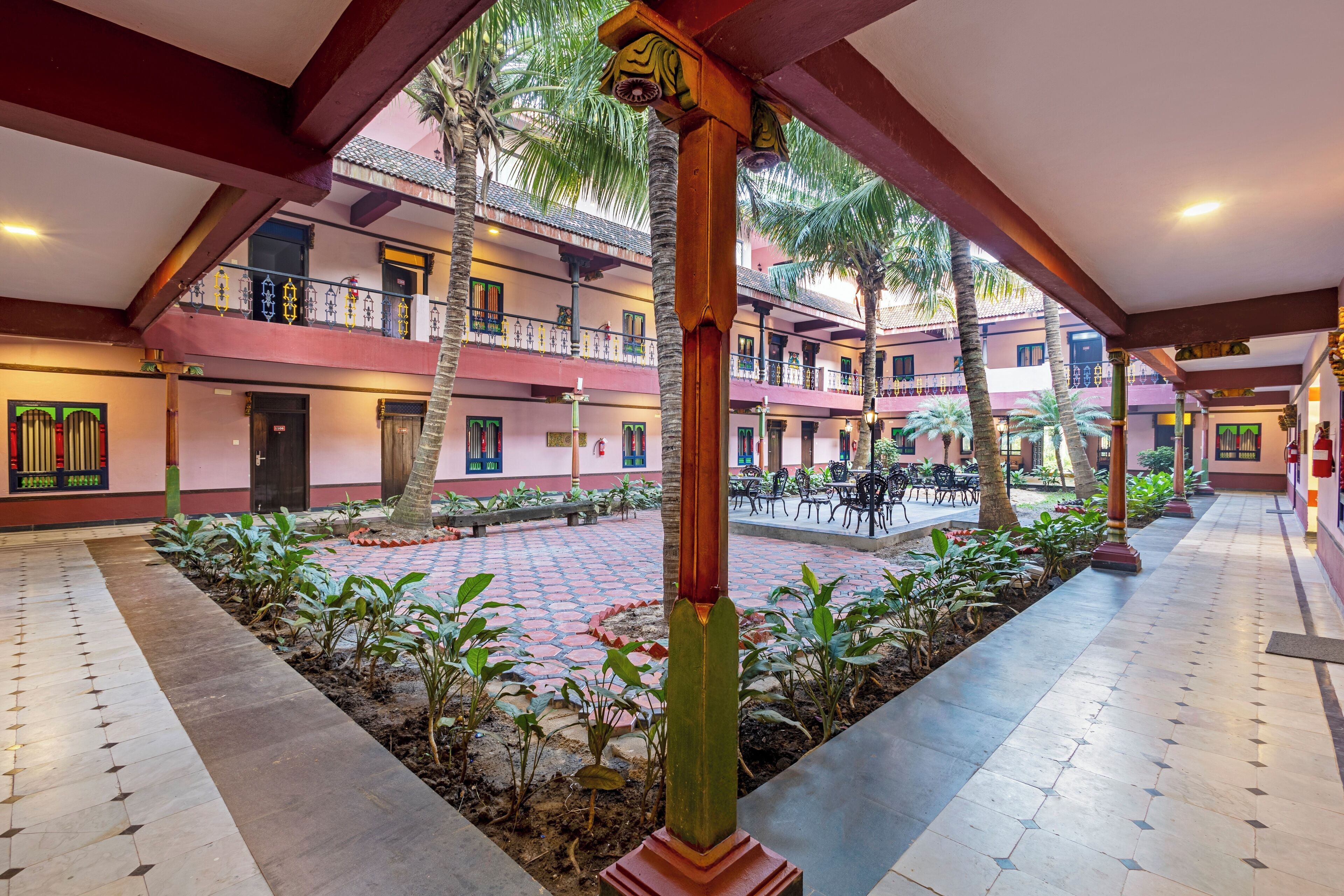 Un patio con suelo de baldosas, palmeras y una columna central.
