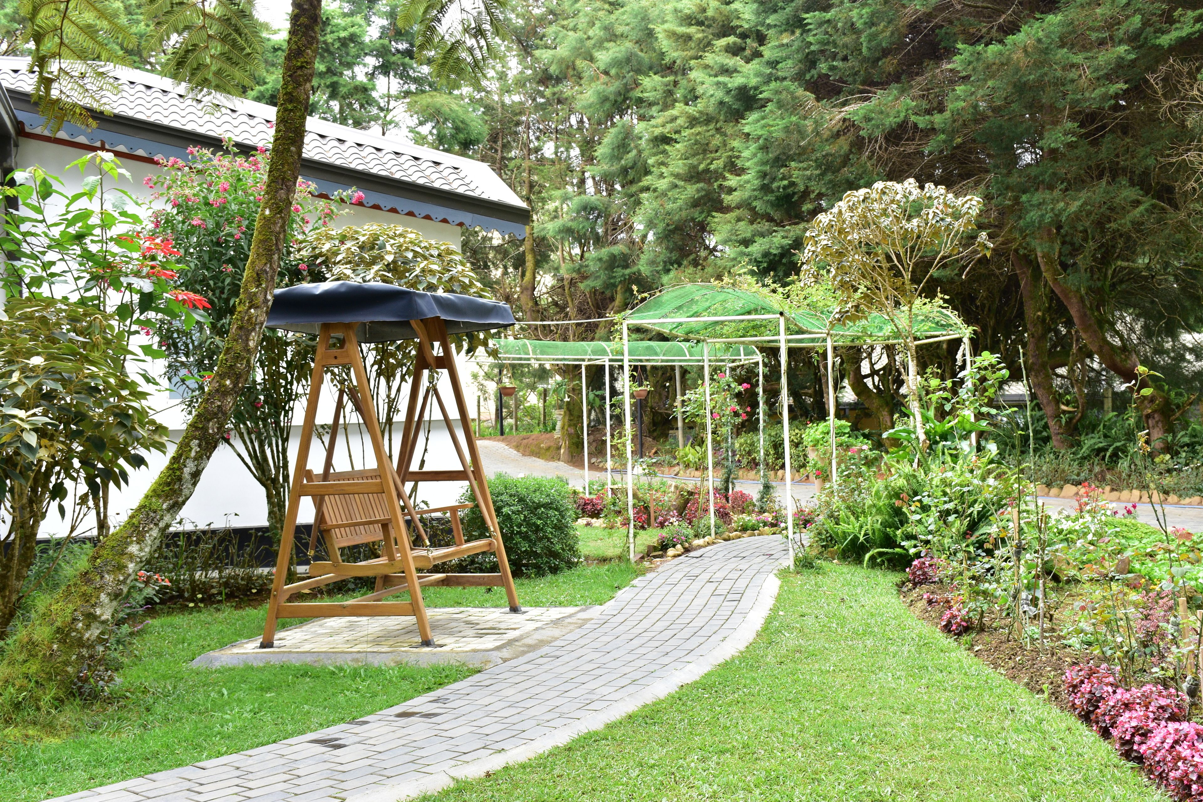 Un jardín con un columpio, un mirador y un sendero.