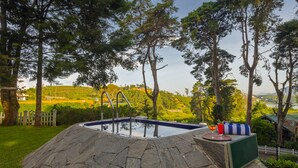 A stone hot tub with a view of a green landscape and hills in the background. - Mirage Kings Cottage (Nuwara Eliya)