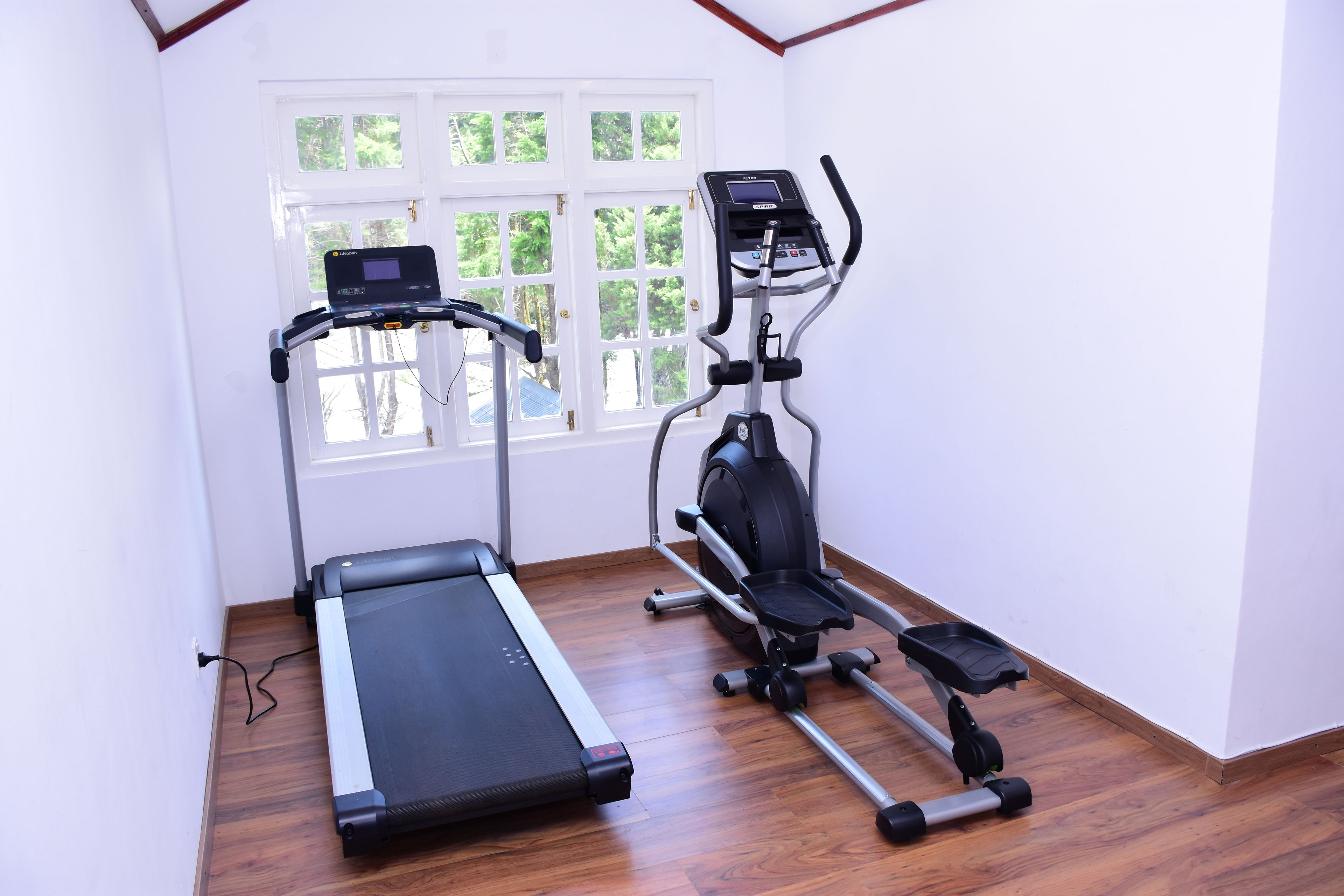 A home gym with a treadmill, elliptical, and stationary bike.