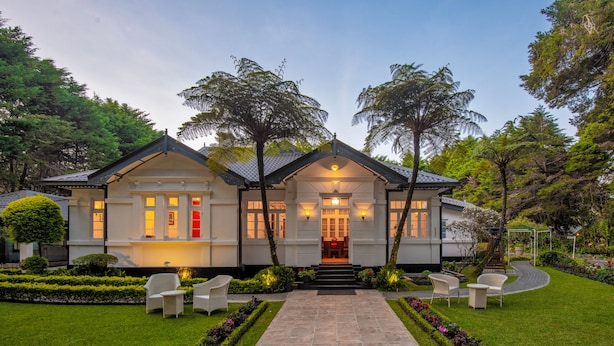 A two-story house with a well-maintained garden, a paved entrance, and outdoor seating. - Mirage Kings Cottage (Nuwara Eliya)