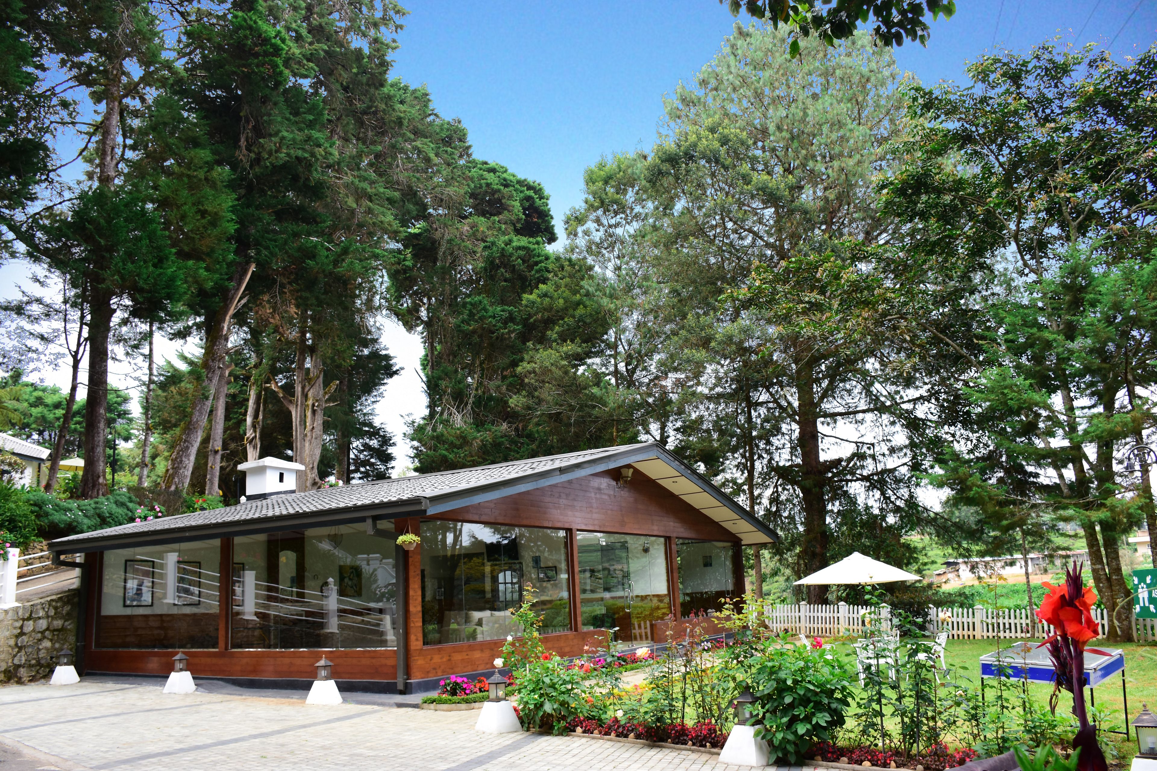 Un bâtiment moderne doté de grandes fenêtres et d’un espace jardin agrémenté de diverses plantes et fleurs.