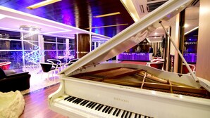 Un piano à queue dans un intérieur moderne, avec un bar en arrière-plan.