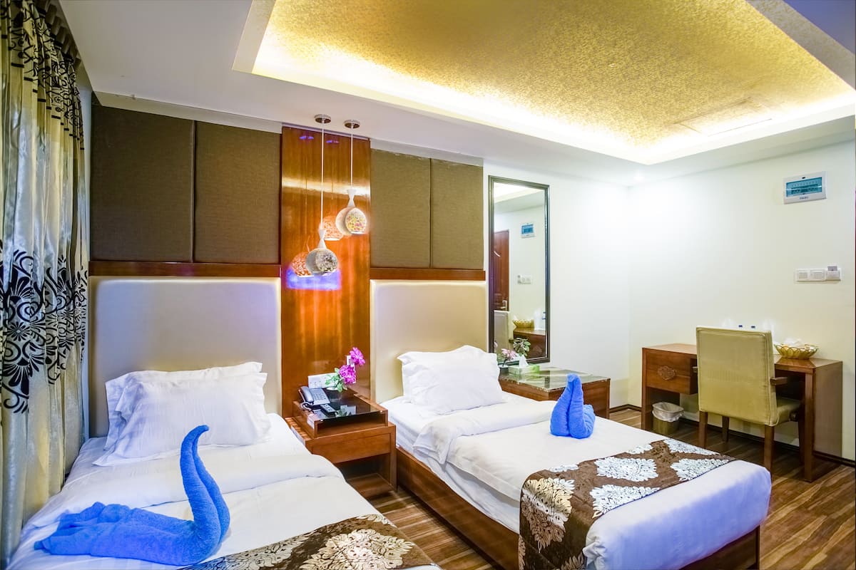 A hotel room with two beds, a desk, and a mirror.