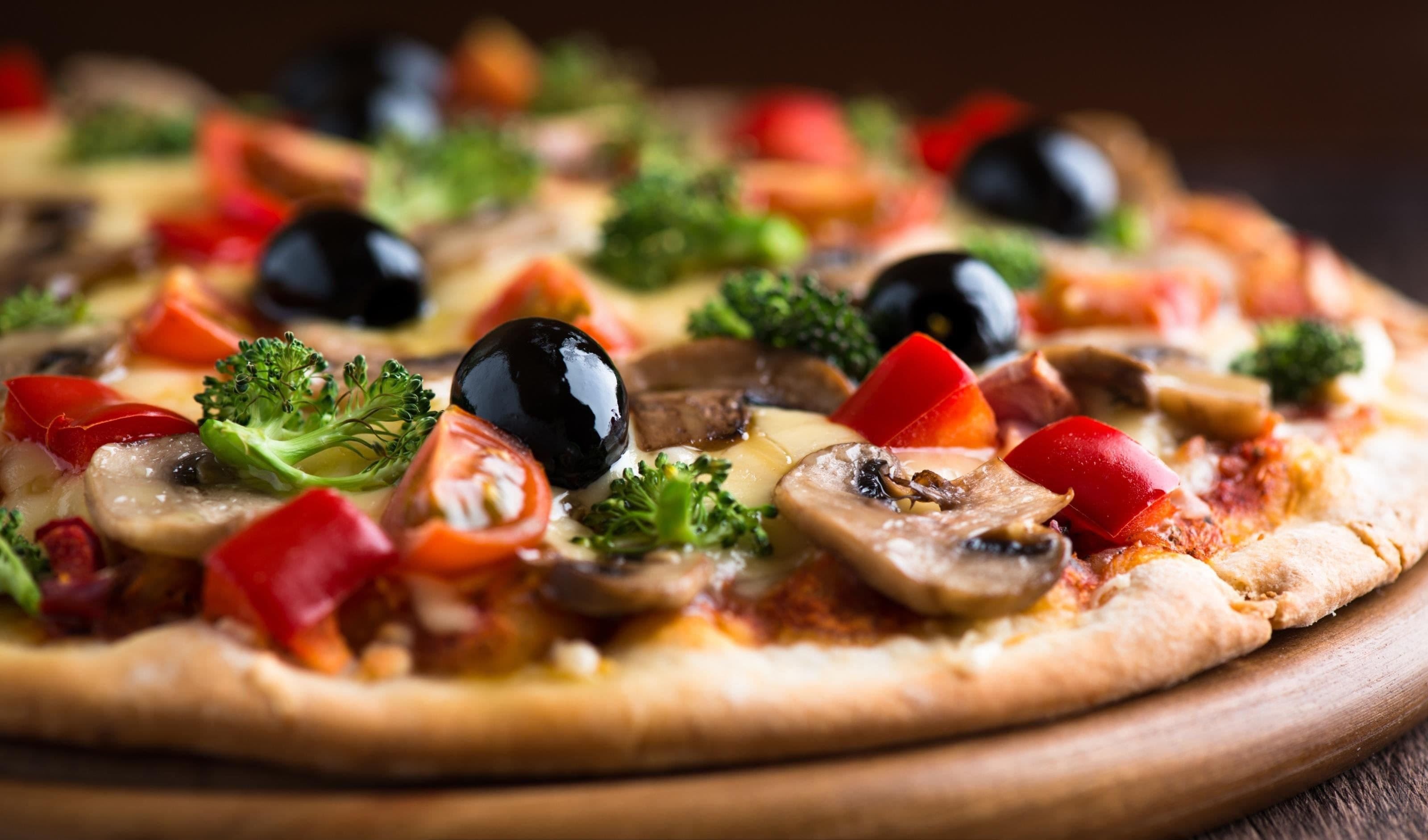 Una pizza con diversi condimenti su un tagliere di legno.