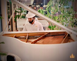 A grand piano in a spacious room with a high ceiling and large windows.