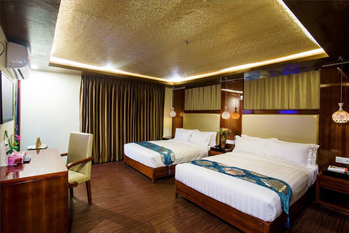 A hotel room with two beds, a desk, and a chair.