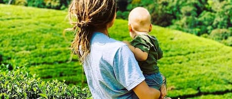 A person holding a child overlooking a green hilly landscape.