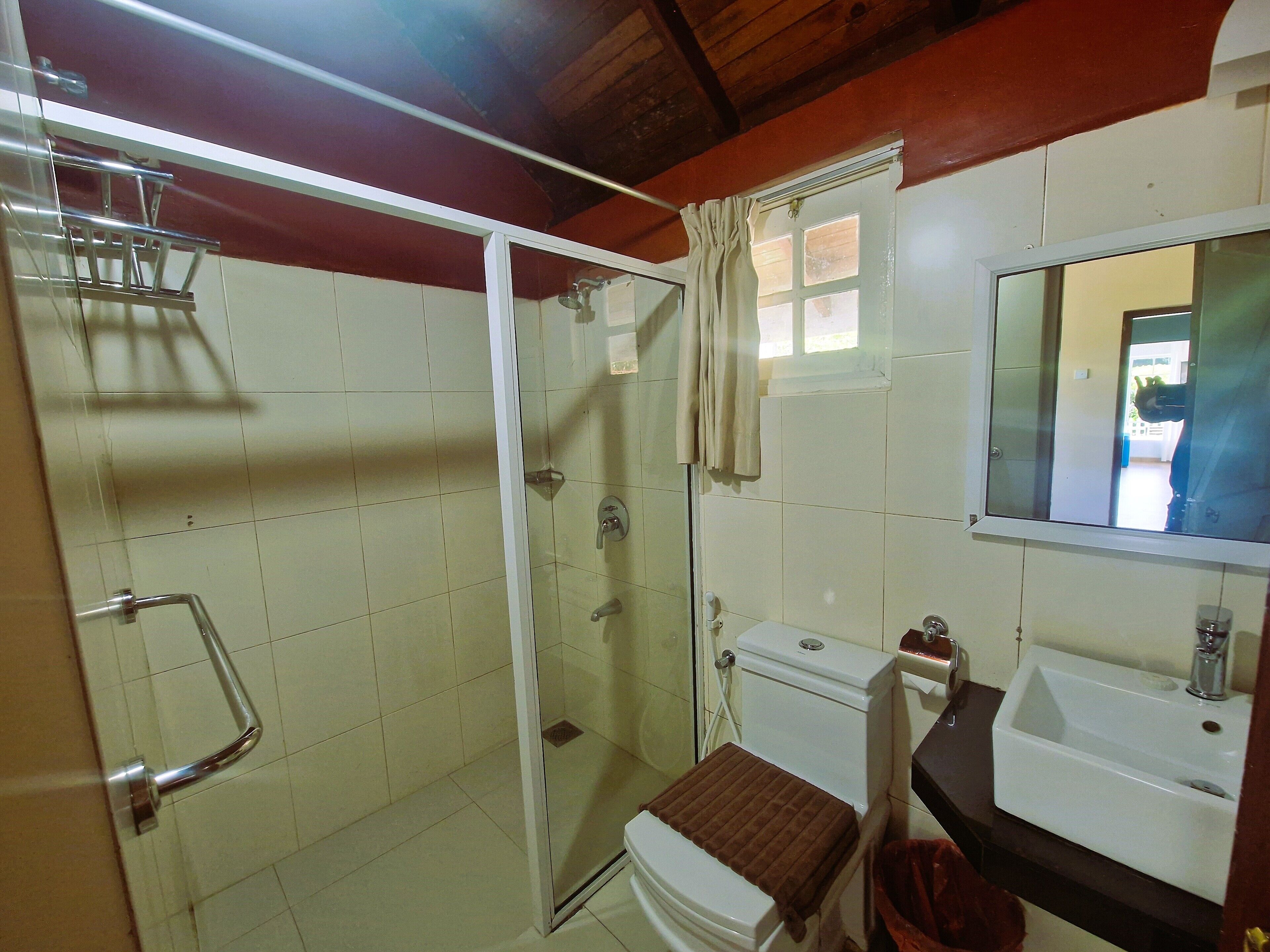 A bathroom with a glass-enclosed shower, a toilet, and a sink.