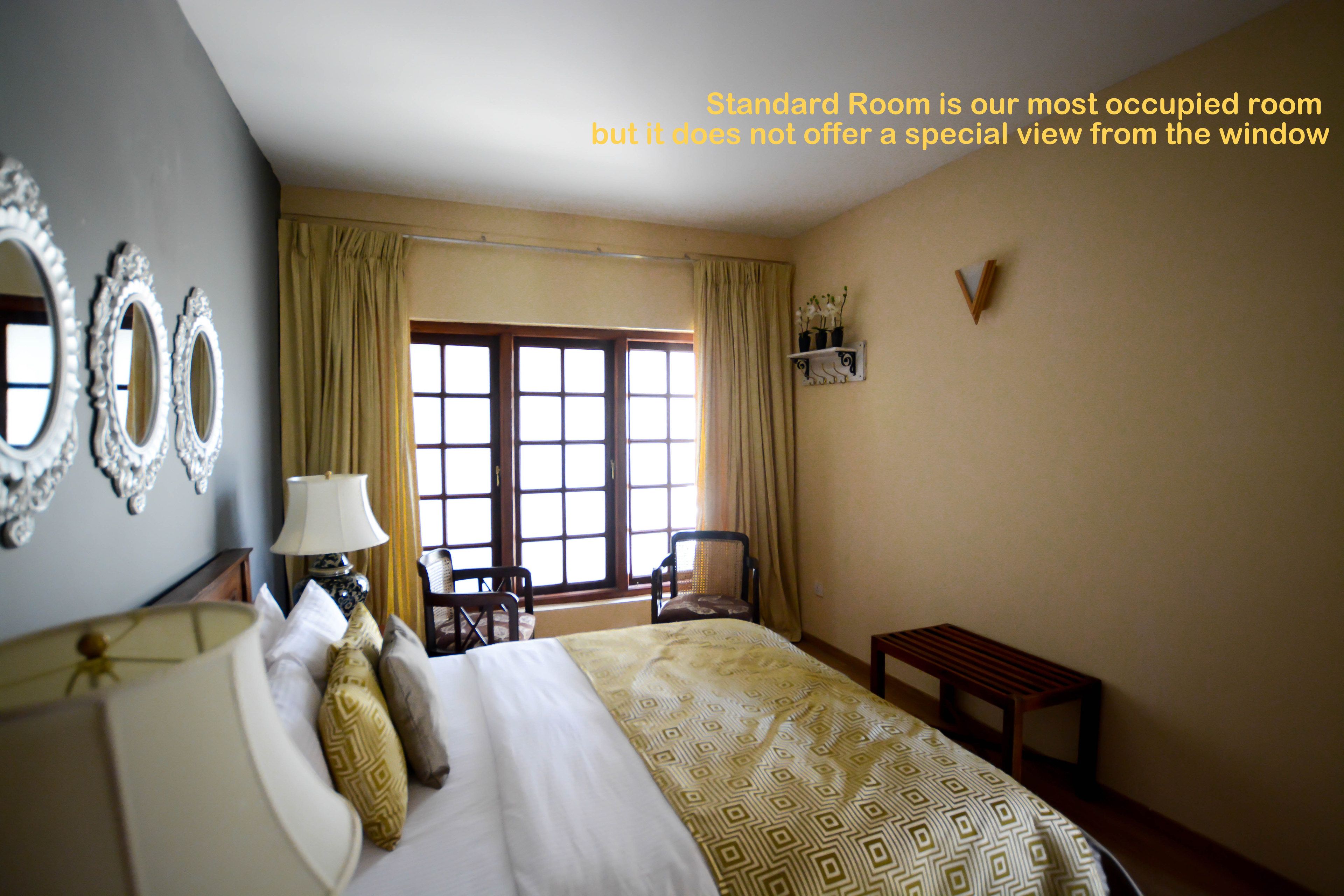 A standard room with a bed, a chair, a table, and a window.