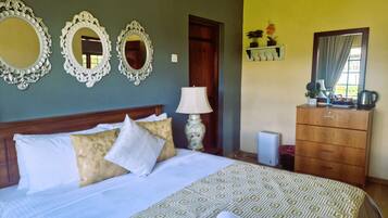A hotel room with a bed, two ornate mirrors, a dresser, and a lamp.
