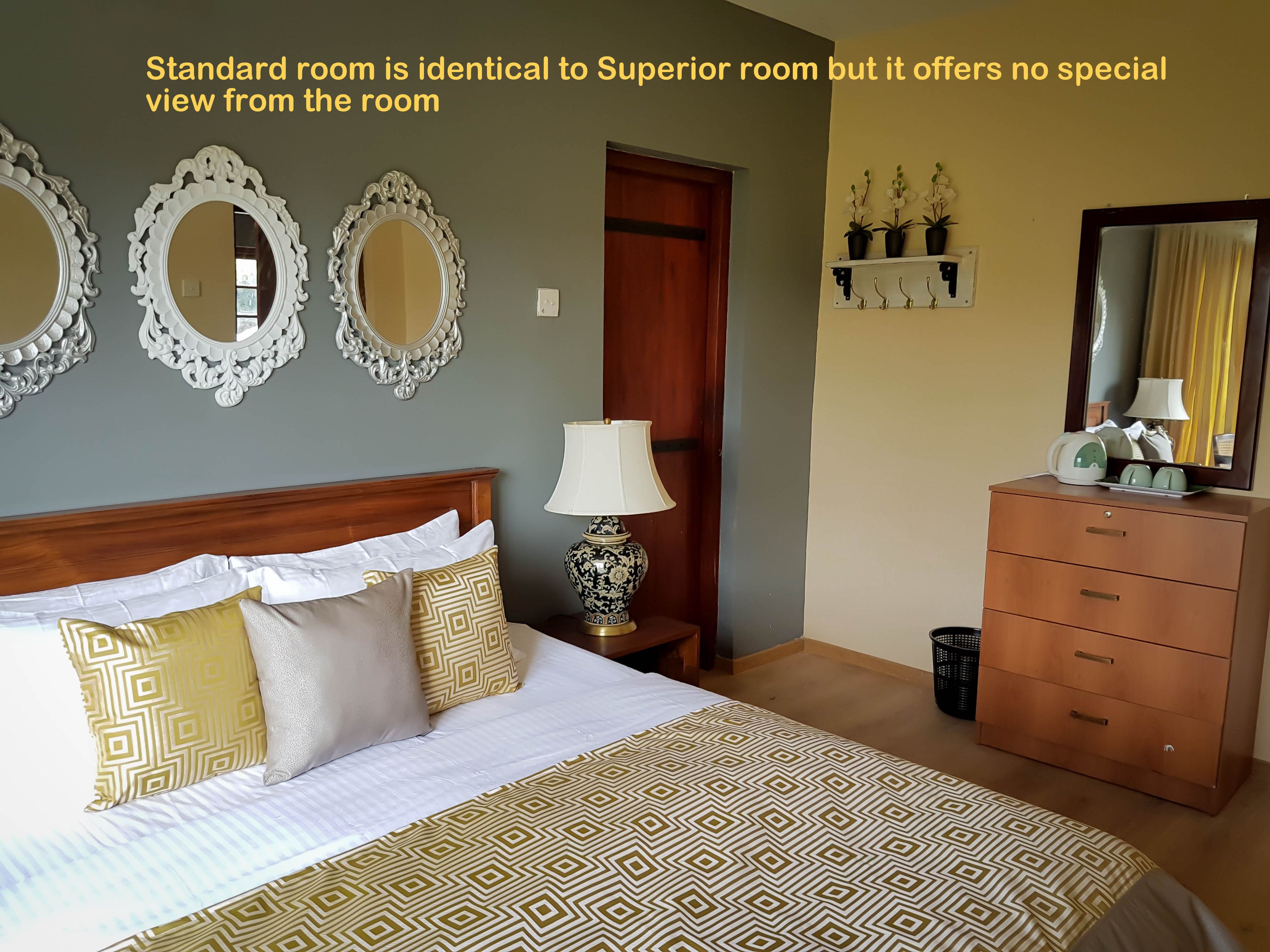 Une chambre d’hôtel standard, équipée d’un lit, d’une commode, de miroirs et d’une lampe.