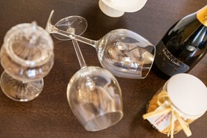 A wooden table with three wine glasses and a bottle of wine. - Hotel Suite Inn (Udine)