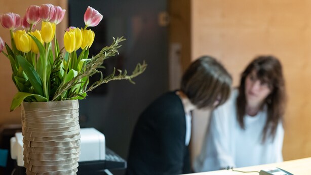 Ein Empfangsbereich mit einer Vase voller Tulpen auf einem Tisch.