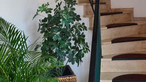 A staircase with wooden steps and black railings, surrounded by framed artwork and potted plants. - Hotel Eifelhof Weina (Heimbach)
