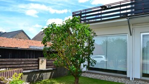 A residential backyard with a tree, a lawn, a wooden fence, and a carport. - Hotel Eifelhof Weina (Heimbach)