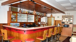 A bar area with a counter, stools, and shelves stocked with bottles and glasses. - Hotel Eifelhof Weina (Heimbach)