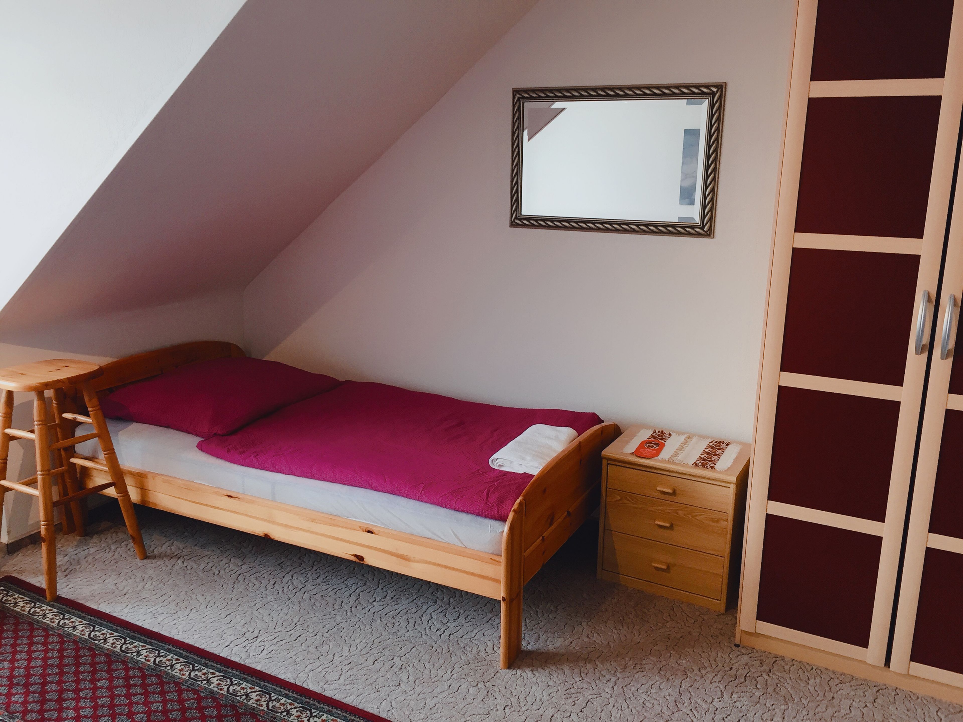 Ett rum i studentkorridorsstil med en våningssäng, ett skrivbord, en stol, en byrå och en garderob.