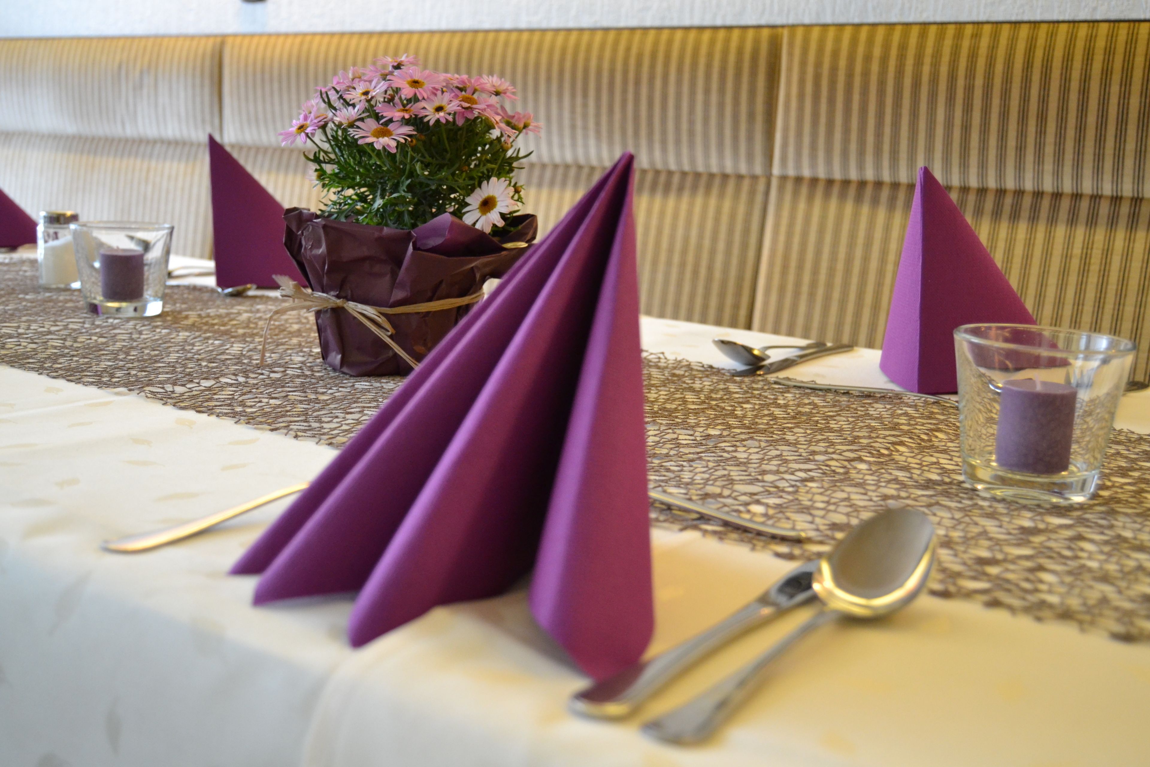 Una mesa dispuesta con servilletas moradas, una vela y un vaso de agua.
