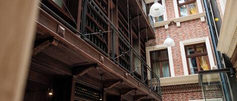 A multi-story building with exposed brickwork, wooden beams, and a series of balconies with railings.