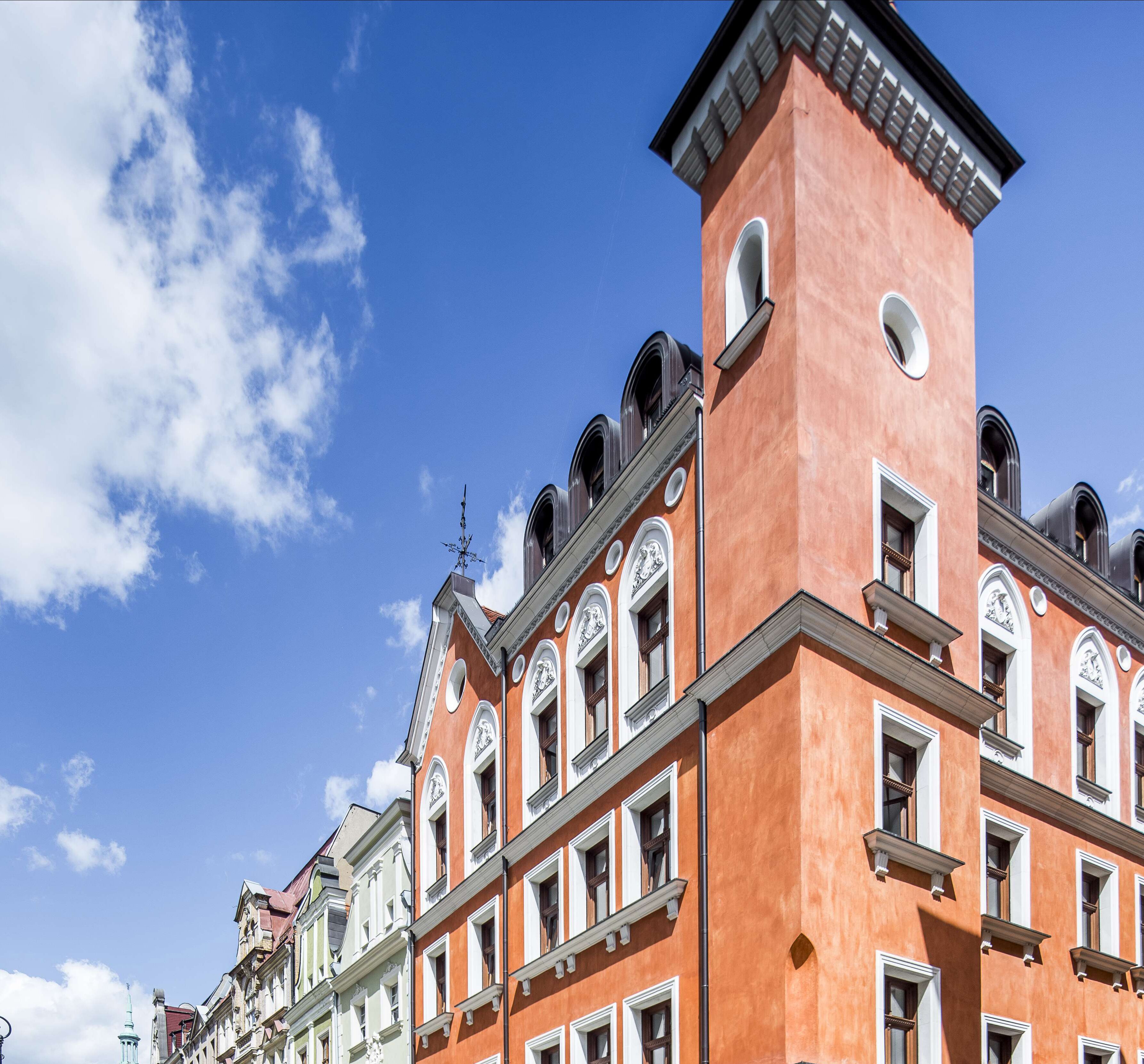 A row of historic buildings with classic architecture, featuring multiple windows and a prominent tower.