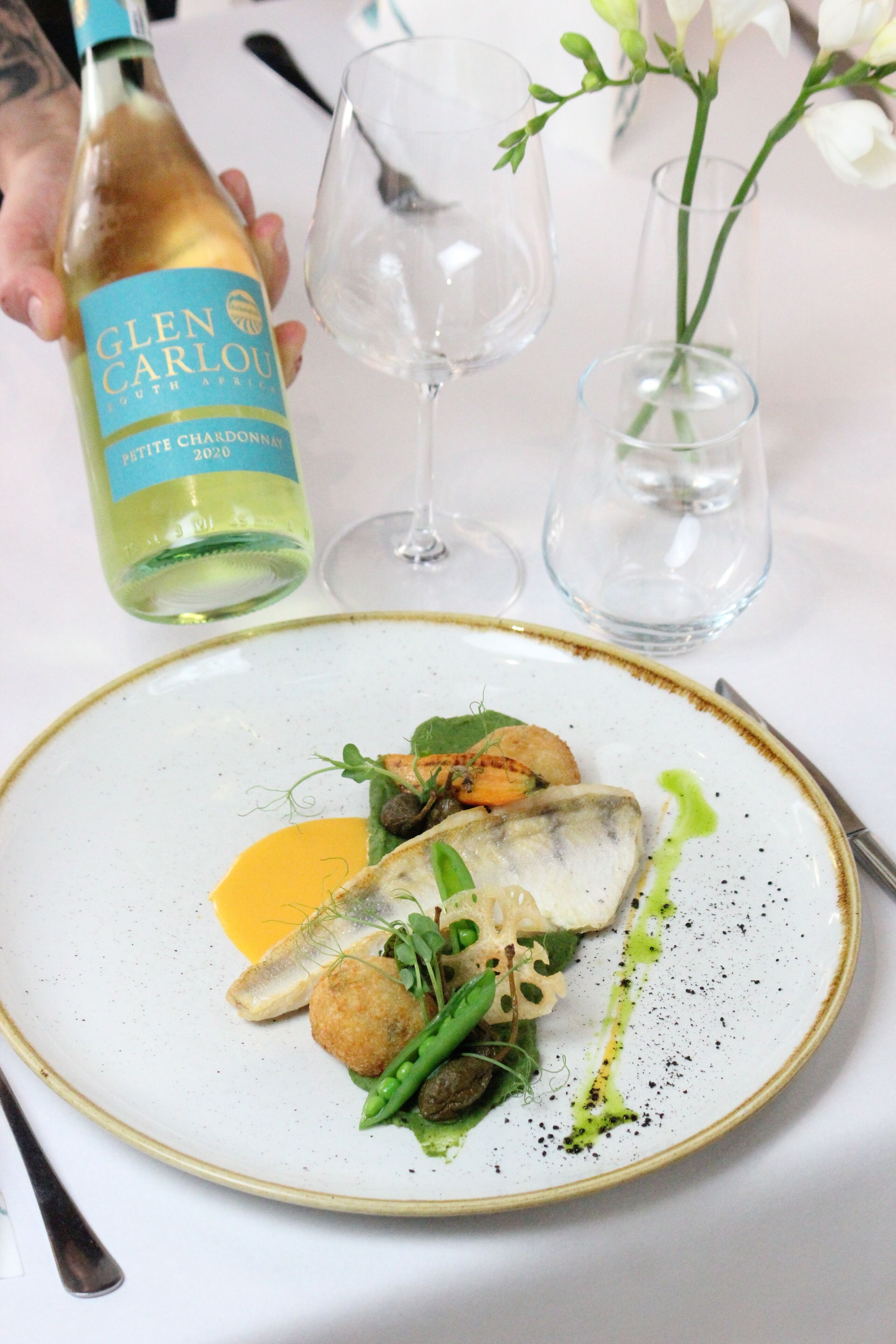 A plate of food with a bottle of Glen Carlou South African Pinot Noir 2020.