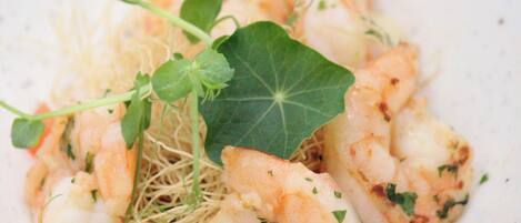 A bowl of shrimp with greens and noodles.