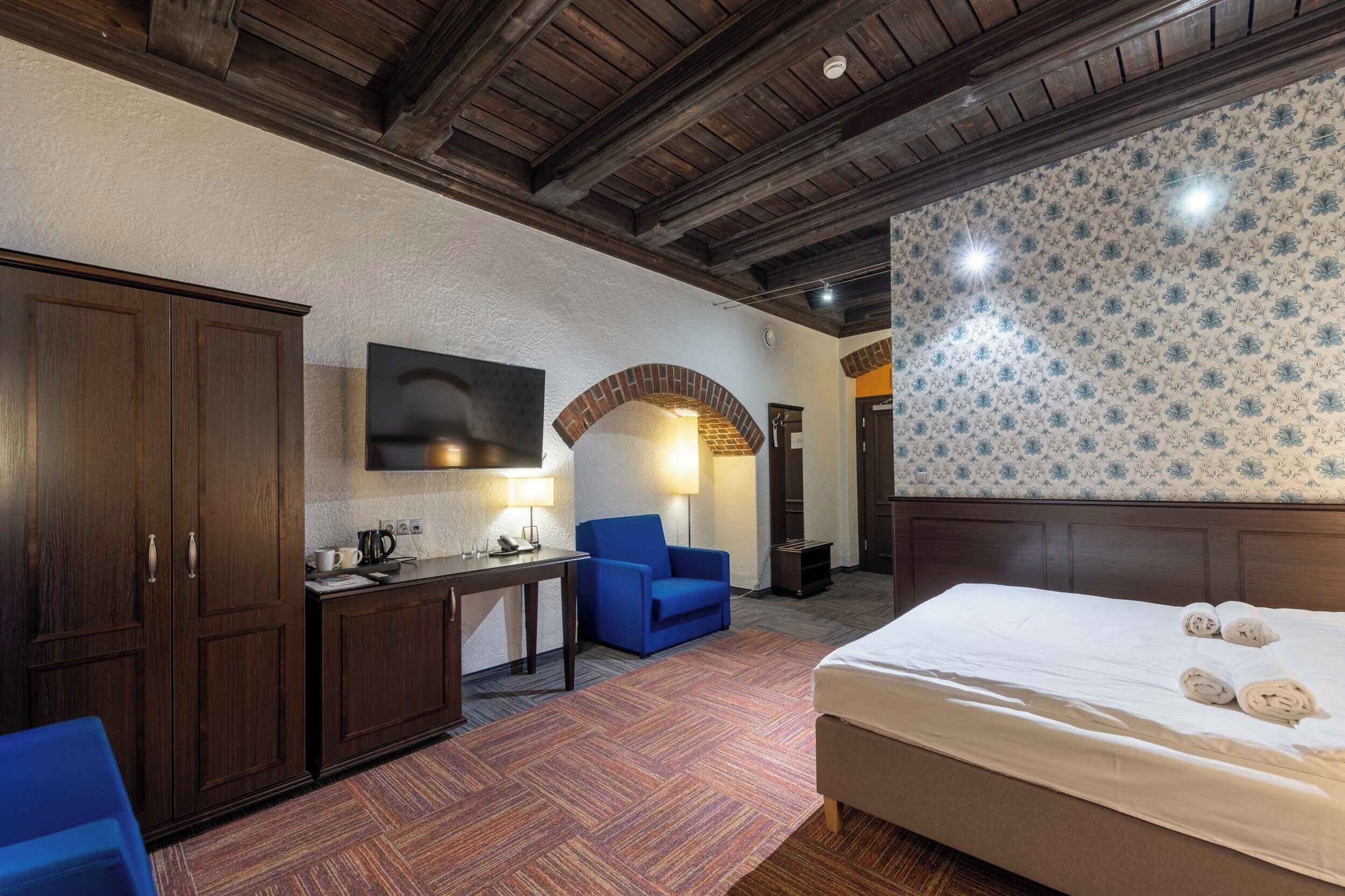 Una habitación de hotel con cama, escritorio, silla y armario.