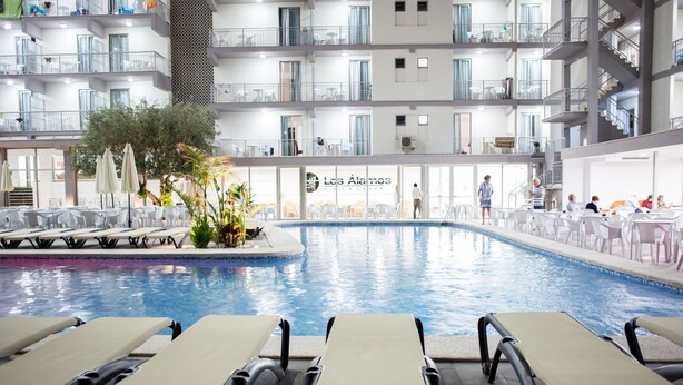 A hotel pool area with lounge chairs, a small pool, and a restaurant in the background. - Hotel Los Alamos (Benidorm)