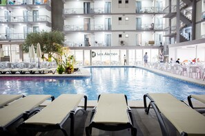 A hotel pool area with lounge chairs, a small pool, and a restaurant in the background. - Hotel Los Alamos (Benidorm)
