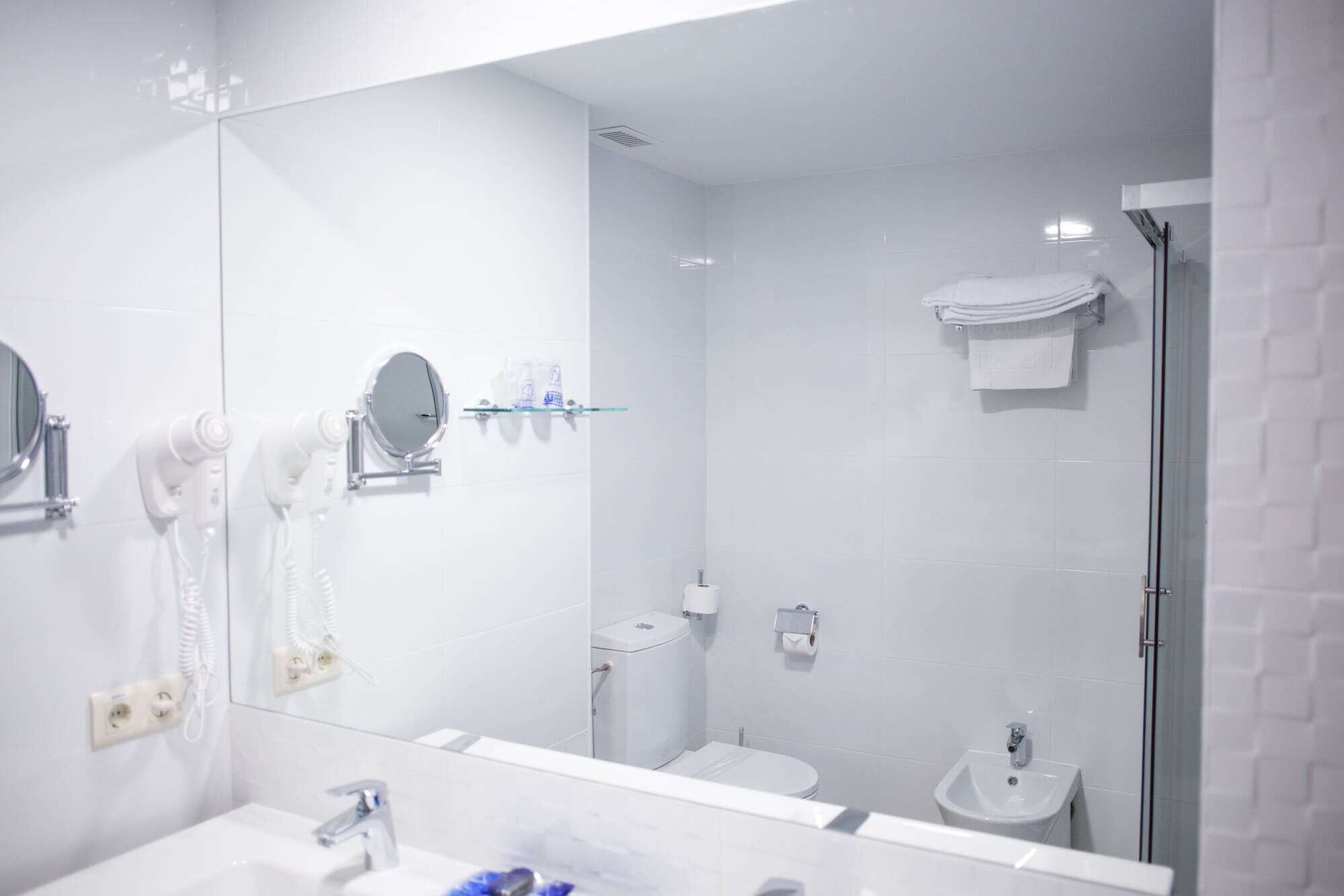 Un baño moderno con un espejo grande, un inodoro, un bidé y un lavamanos.