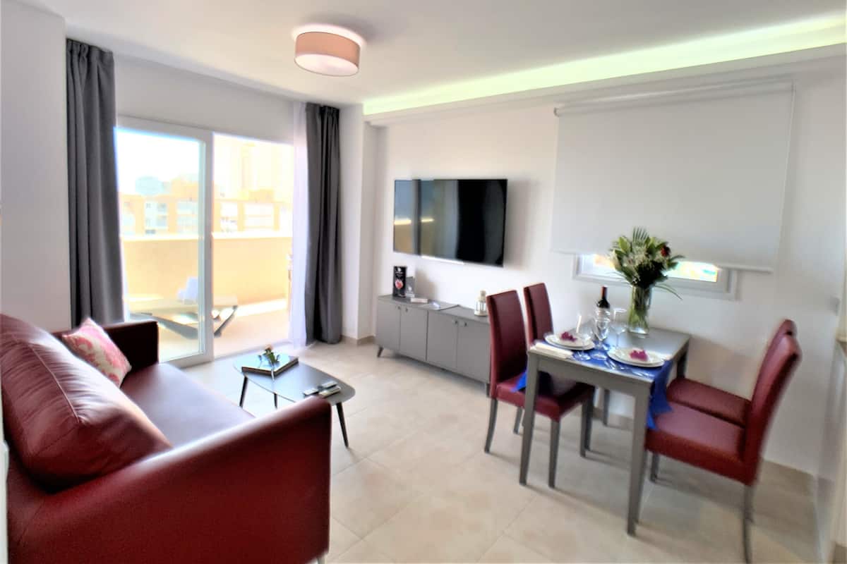 Una sala de estar moderna con sofá, mesa de comedor, sillas y televisor.