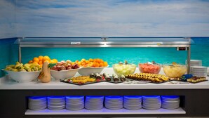 A buffet with various fruits and desserts, a view of the ocean, and stacks of plates. - Hotel Los Alamos (Benidorm)