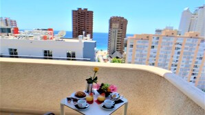 A balcony with a table set for two, overlooking a cityscape with high-rise buildings and a clear sky. - Hotel Los Alamos (Benidorm)