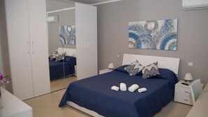 Un dormitorio con cama, mesitas de noche, armario y una obra de arte abstracta en la pared.