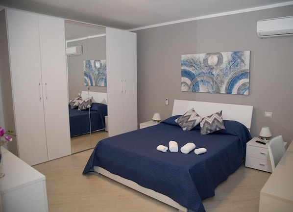 A bedroom with a bed, nightstands, a wardrobe, and abstract wall art.