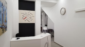 Un mostrador de recepción con una nube de palabras en la pared, un reloj y un cuadro.