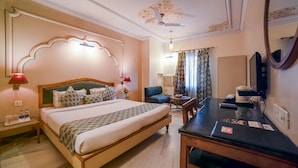 Habitación de hotel con una cama grande, un escritorio, una silla, un televisor y un ventilador de techo.