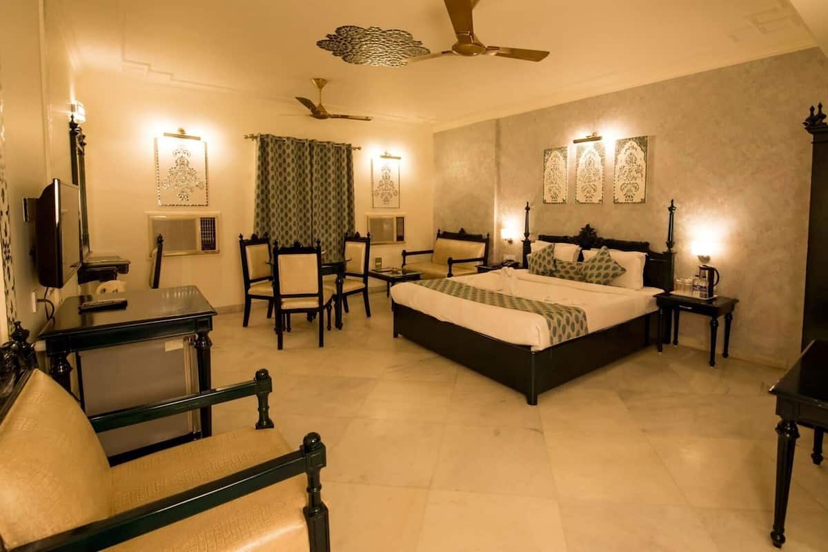 A bedroom with a bed, a desk, a chair, a TV, and a ceiling fan.