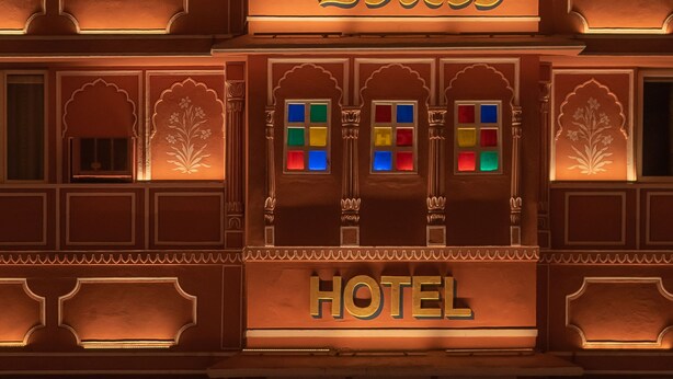 Un edificio de varios pisos con elementos arquitectónicos tradicionales, incluyendo ventanas de arco y motivos decorativos. El edificio tiene un letrero que dice “HOTEL” y el número “1727” encima.