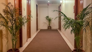 Un pasillo de hotel con piso alfombrado, puertas de madera y plantas en macetas.