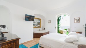 Un dormitorio con cama, escritorio, silla, cómoda y un amplio ventanal con vistas al exterior.