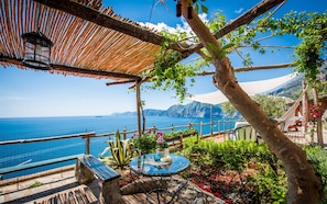 A seaside patio with a table, chairs, and a hanging lantern. - Calanteluna (Praiano)