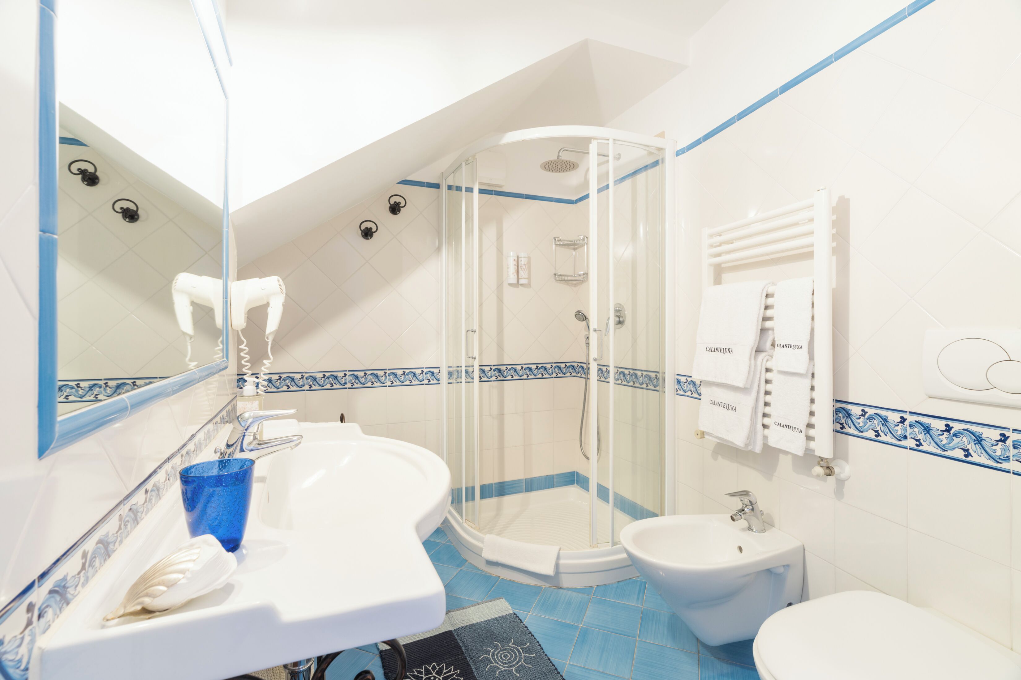 A bathroom with a shower, bidet, and a sink.