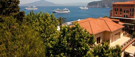A coastal view with cruise ships and a building with "EXCELSIOR VITTORIA" signage.