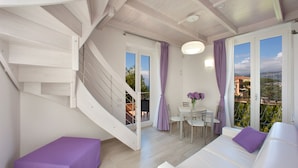 A modern interior with a staircase, a dining area, and a sofa with purple cushions. - Al Centro Suites (Sorrento)